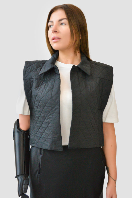 Model wearing black adaptive quilted gilet over white T-shirt, shown with prosthetic arm

