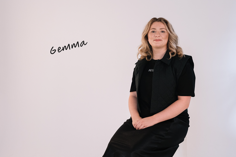 Gemma McAllister seated in studio wearing black WearMatter outfit with quilted vest, against a soft white background