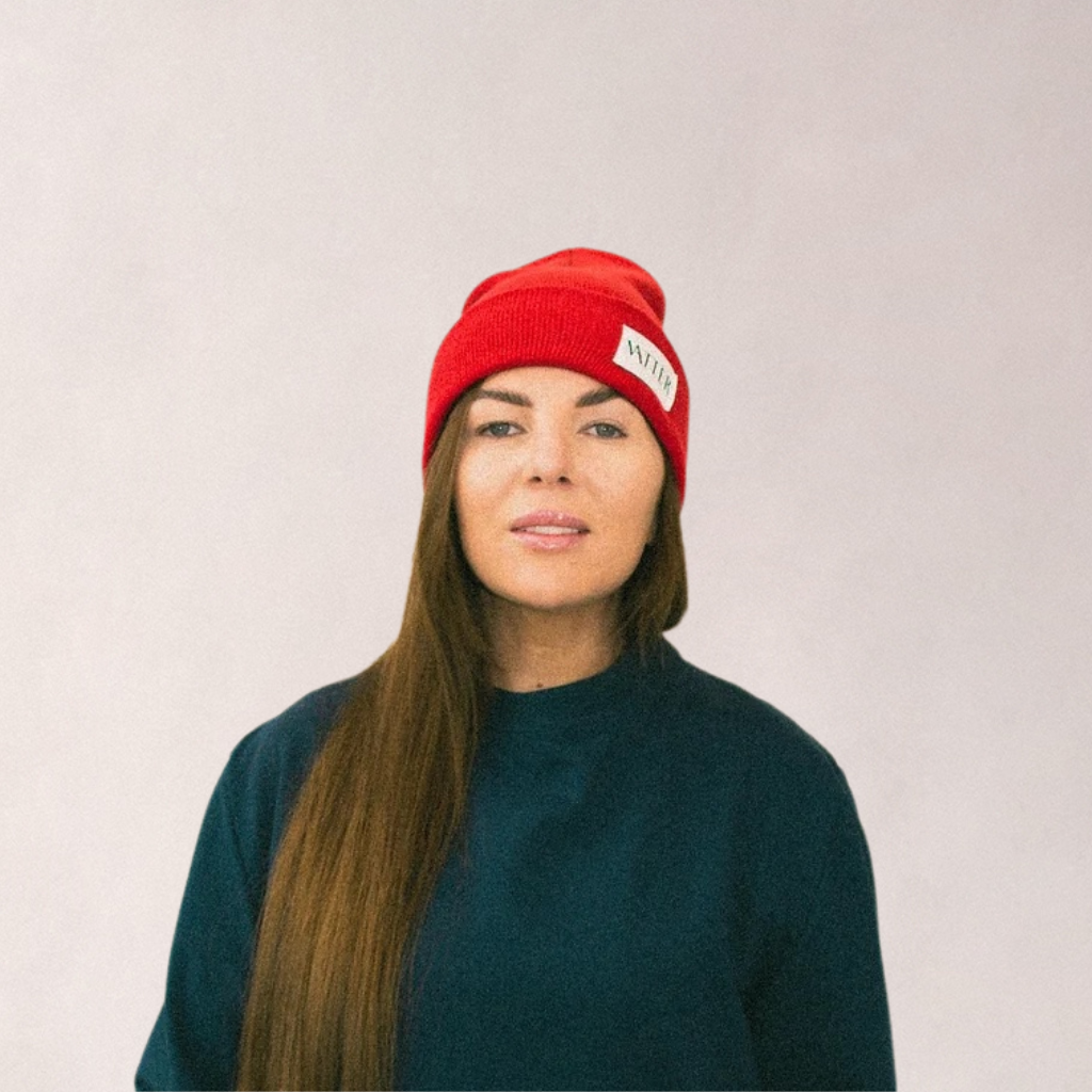 Woman wearing a red knit beanie with folded brim and WearMatter Matter label, inclusive fashion accessory