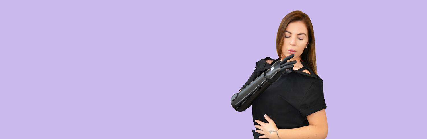 Woman with prosthetic arm fastens WearMatter adaptive T-shirt using magnetic shoulder closure on a purple background.